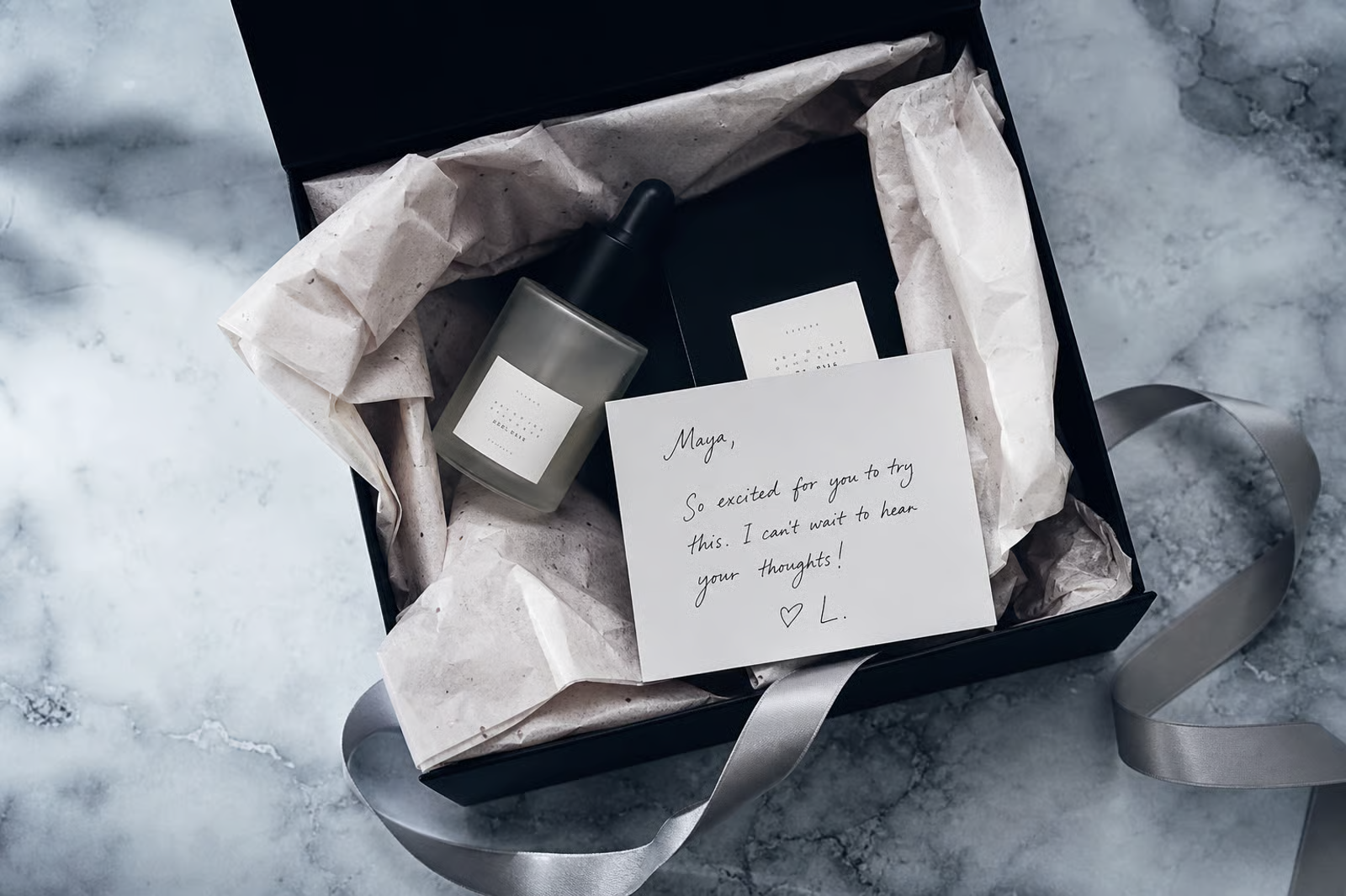 A luxury PR gift box with a candle, dropper bottle, ribbon, and a handwritten note reading 'So excited for you to try this'