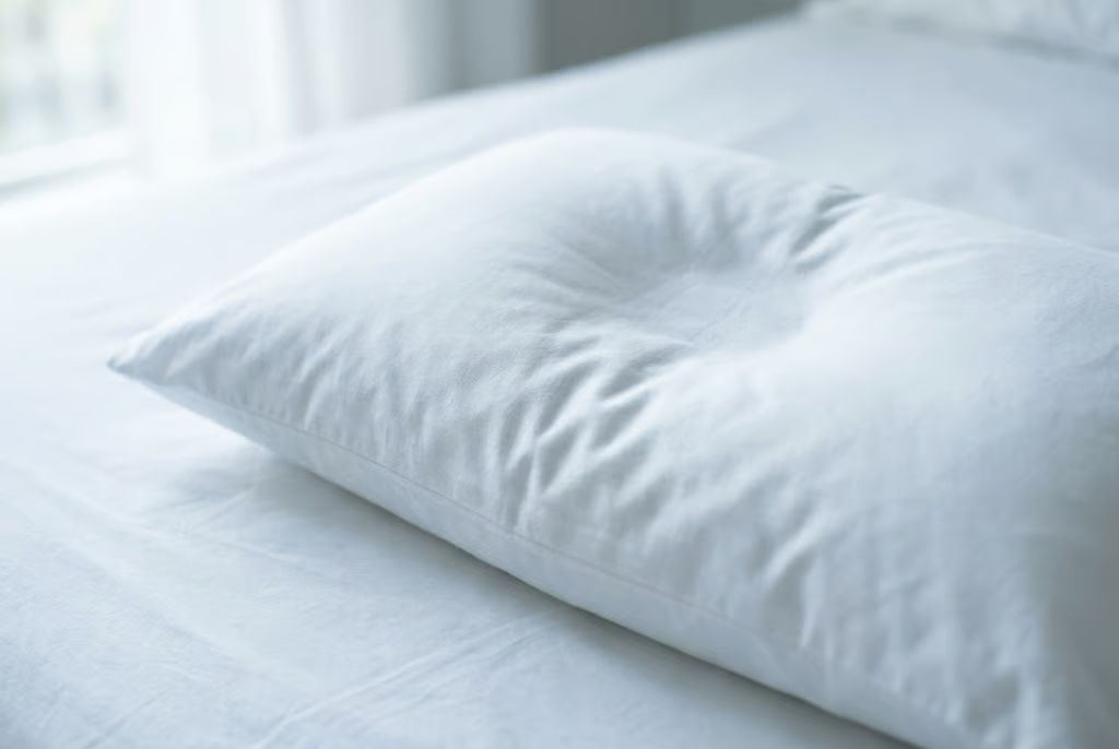 A clean white pillow on freshly made bedding